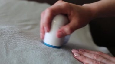 Giysilerdeki topakları bir kadının elinden almak için bir cihaz, yakın plan.