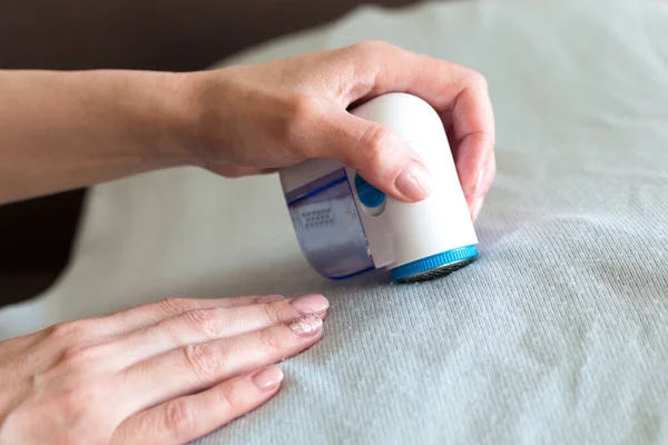 Giysilerdeki topakları bir kadının elinden almak için bir cihaz, yakın plan..