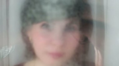 Evde cam yıkayan bir kadın bez parçasıyla cam siliyor..