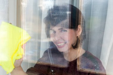 45 yaşında esmer bir kadın apartmanın camını yıkıyor. Bulanık resim, odak yok