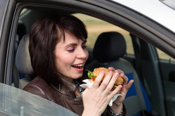 Mosolygó Egy Autóban Hamburgerrel Kezében — Stock Fotó