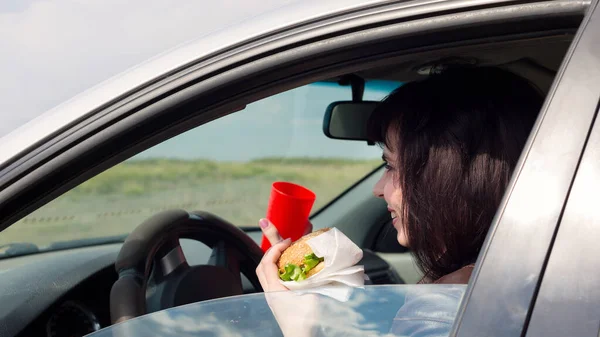 Mulher Sorridente Carro Dirigindo Com Hambúrguer — Fotografia de Stock