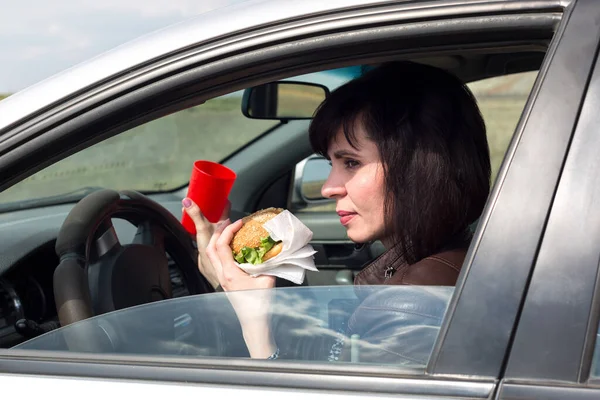 Kobieta Samochodzie Hamburgerem Szklanką Ręku — Zdjęcie stockowe