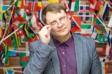 Farklı ülkelerin bayraklarının arka planında Uluslararası İlişkiler Fakültesi Dekanı.