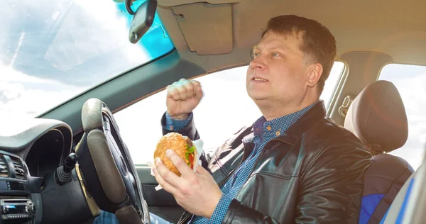 Bardzo Zadowolony Kierowca Kierownicą Samochodu Korzysta Hamburgera — Zdjęcie stockowe