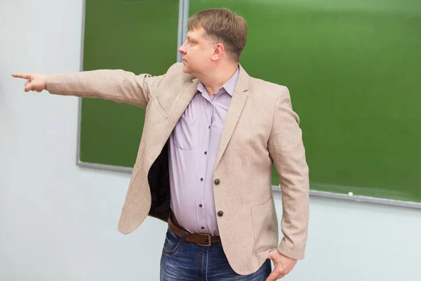 ブラックボードの物理の先生は学生に手のジェスチャーで教室からの出口を示しています — ストック写真