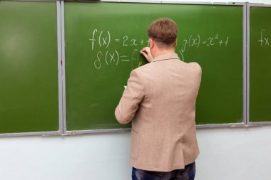 Bir matematik öğretmeni öğrencilere okul tahtasındaki bir sorunun çözümünü gösterir..