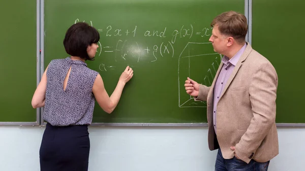 老师向学生解释黑板上数学题的解法 — 图库照片