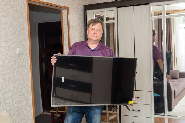 Yetişkin Sarışın Bir Adam Odaya Büyük Bir Televizyon Getiriyor — Stok fotoğraf