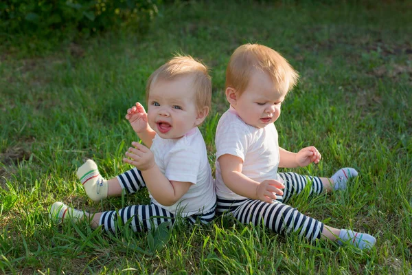 Tvillingflickor Sitter Det Gröna Gräset Med Ryggen Mot Varandra — Stockfoto