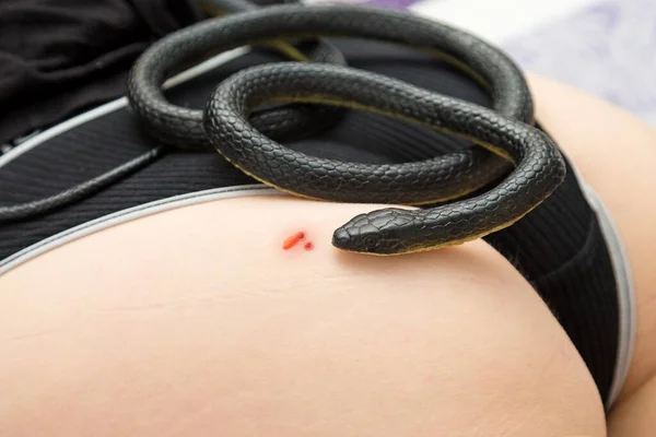 A venomous snake lies on body of a bitten woman in her underwear.