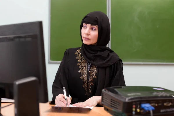 Muslim girl teacher working with school documents.