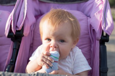 Küçük bir çocuk ayağını ağzına aldı ve onunla dişlerini tırmalıyor. Diş çıkarma..