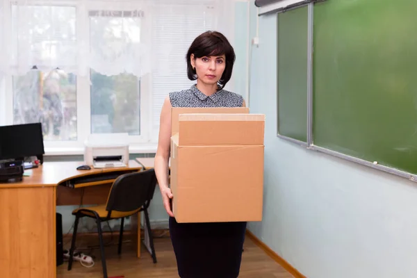 Kovulan üzgün öğretmen okul ofisinden bir kutu eşyayla ayrılıyor..