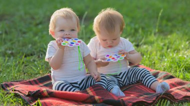 Hafif giysili kız kardeşler çimenlerin üzerinde aileleri olmadan otururlar..