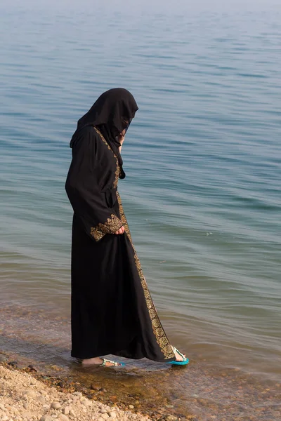 民族衣装を着たイスラム教徒の女性が足を海に濡らし — ストック写真