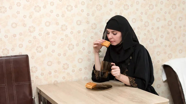 一位穿着民族服装的穆斯林妇女在公寓的餐桌边吃早餐 — 图库照片