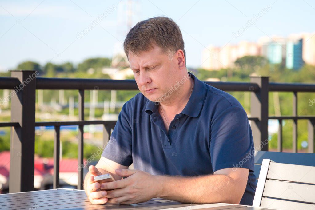 A man in an outdoor cafe at a table enjoying nature while waiting for his order.