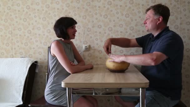 一个男人和一个女人正在桌边切甜瓜 谈论着过去的一天 — 图库视频影像