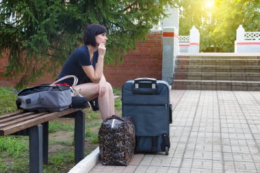 Tren istasyonunda bir bavulla bankta sıkılmış bir kadın trenini bekliyor..