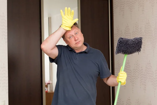 黄色いゴム手袋を手にした男はアパートを掃除した後疲労で額をこすり — ストック写真