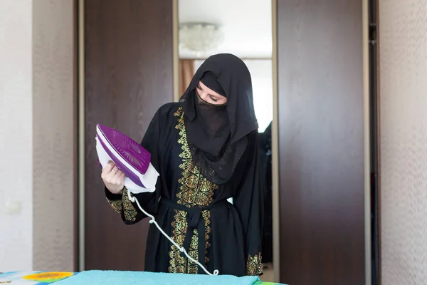 Мусульманская Женщина Национальной Одежде Гладит Одежду Своей Квартиры — стоковое фото
