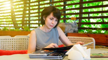 Lokantadaki esmer bir kadın menüye bakar masada otururken yemek seçer..