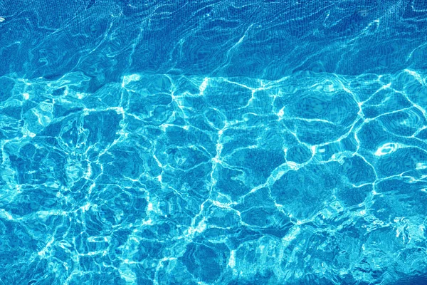 Fondo de agua. Agua de la piscina rasgada azul, reflejos del sol — Foto de Stock