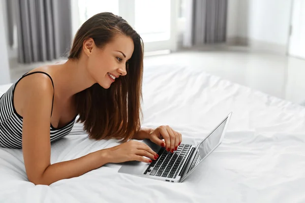 Жінка купує онлайн. Усміхнена дівчина використовує ноутбук комп'ютер вдома — стокове фото