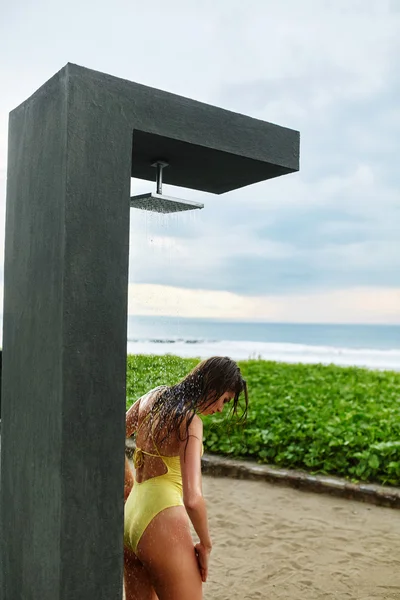 Mujer tomando ducha en playa por piscina —  Fotos de Stock