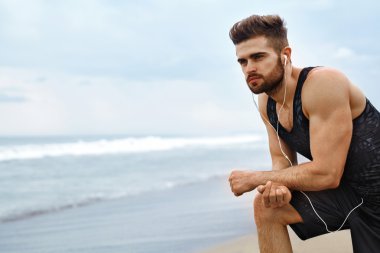 Yorgun bir adam sahilde çalıştırdıktan sonra dinlenme. Spor iş açık