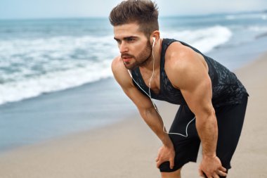 Yorgun bir adam sahilde çalıştırdıktan sonra dinlenme. Spor iş açık