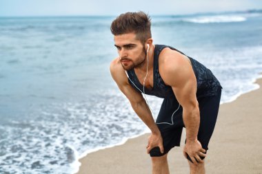 Yorgun bir adam sahilde çalıştırdıktan sonra dinlenme. Spor iş açık