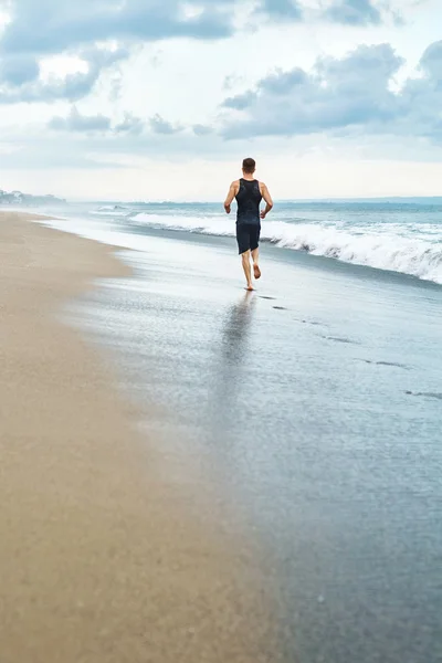 Hombre Fitness corriendo en la playa. Corredor corriendo durante el entrenamiento al aire libre — Foto de Stock