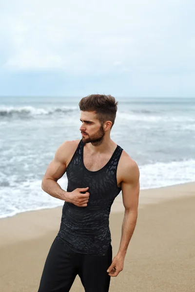 Schöner Mann mit muskulösem Körper in Sportbekleidung am Strand. — Stockfoto
