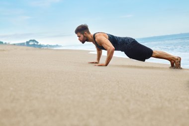 Egzersiz, itme yapıyor fitness adam Ups egzersiz sahilde. Spor