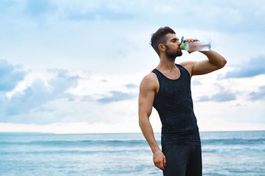 Man Drinking Refreshing Water After Workout At Beach. Drink