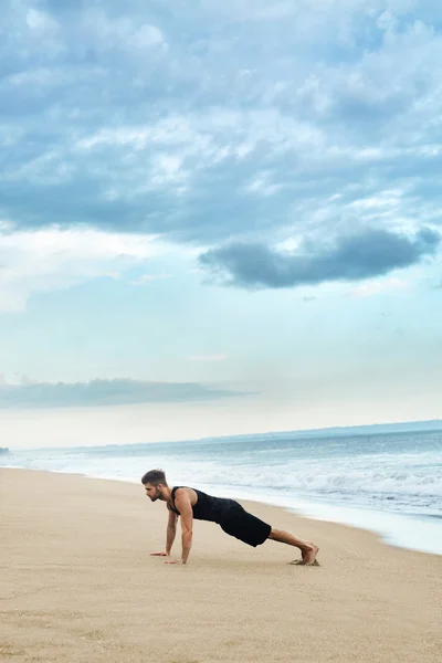 Hombre haciendo ejercicio de empuje en la playa. Concepto de ejercicio corporal — Foto de Stock