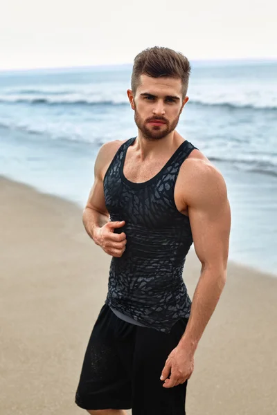 Hombre guapo con ajuste cuerpo muscular en ropa deportiva en la playa . — Foto de Stock