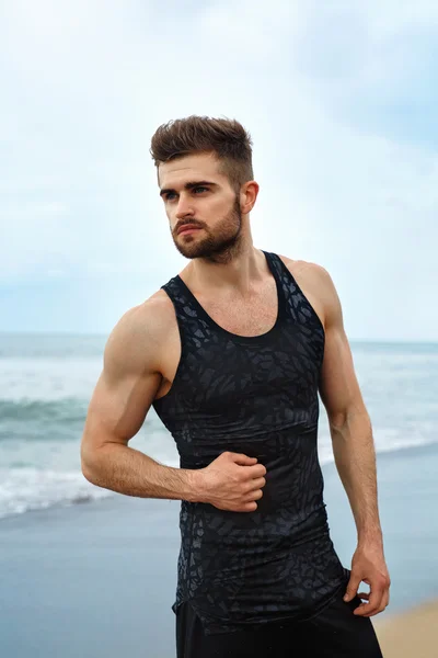 Bonito homem com ajuste corpo muscular em Sportswear na praia . — Fotografia de Stock