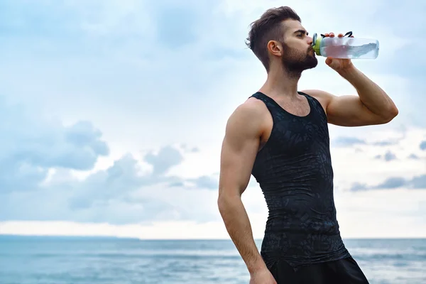 Homme boire de l'eau rafraîchissante après l'entraînement à la plage. Buvez — Photo