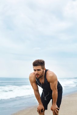 Yorgun bir adam sahilde çalıştırdıktan sonra dinlenme. Spor iş açık