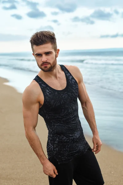 Hombre guapo con ajuste cuerpo muscular en ropa deportiva en la playa . — Foto de Stock