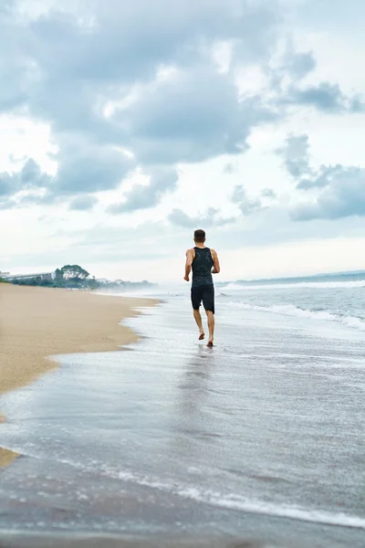 Hombre Fitness corriendo en la playa. Corredor corriendo durante el entrenamiento al aire libre —  Fotos de Stock