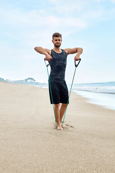 Fitness Hombre Ejercicio en la playa, Hacer ejercicio Expansor al aire libre — Foto de Stock