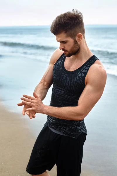 Hombre guapo con ajuste cuerpo muscular en ropa deportiva en la playa . — Foto de Stock