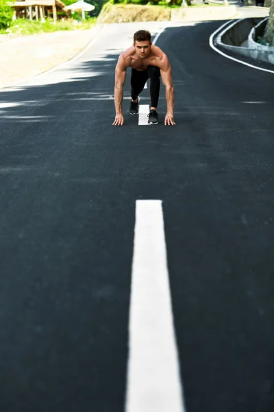 Hombre atlético listo para empezar a correr al aire libre. Concepto de entrenamiento deportivo — Foto de Stock