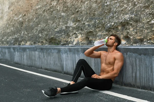 Heißdurstiger Mann trinkt nach dem Laufen im Freien Wasser. Sport — Stockfoto