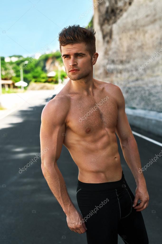 Bonito sexy fitness homem com corpo muscular ao ar livre no verão