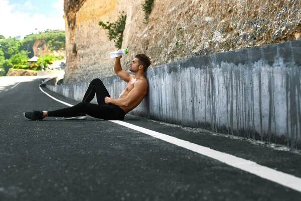 Hombre caliente vertiendo agua refrescante sobre la cara después de hacer ejercicio al aire libre — Foto de Stock
